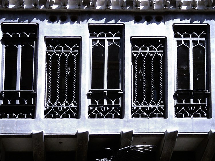 Дворец Гуэля. Главный фасад, выходящий на узкую улицу Nou de la Rambla. Декоративные ажурные решетки из кованого металла, заполняют чисто геометрические - прямоугольные - оконные проемы эркера. Орнамент решеток сдержан, как "росчерк пера".