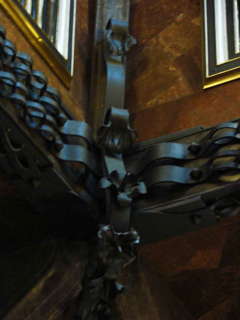 Дворец Гуэля. Нижний выступ второго этажа над Центральным салоном, украшенный по углам цветочным орнаментом и лентами из кованого железа. Орнаменты зрительно скрепляю 4 угла навеса.