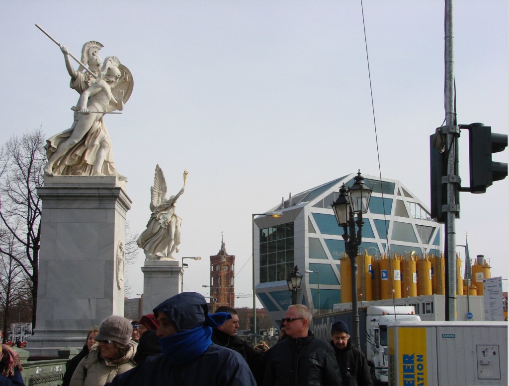 Унтер-ден-Линден (бульвар Под Липами) за Арсеналом при переходе через Шпрею по Дворцовому мосту с воинственной скульптурой - новоделом (всего 6 скульптур). В перспективе - башня Ратуши, где все дела города решают.